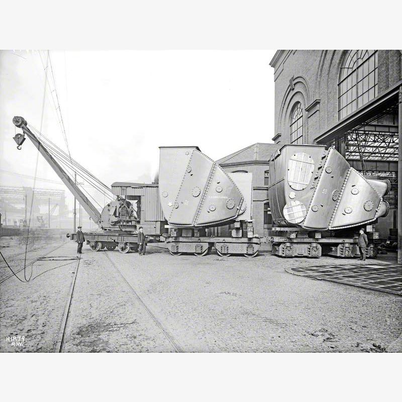 Condensers on trucks being towed out of shop by steam crane