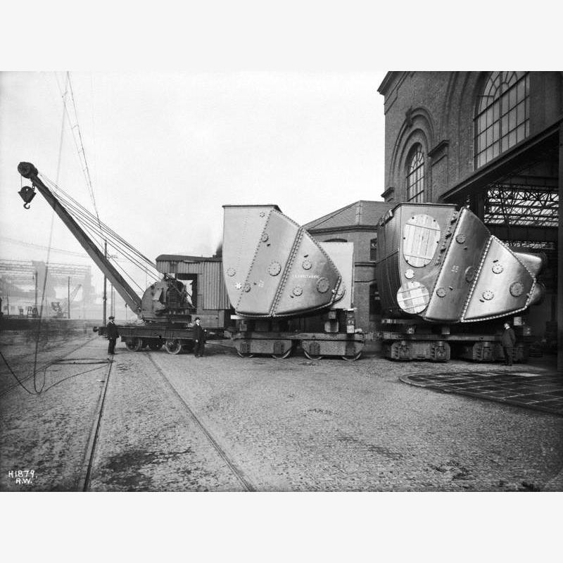 Condensers on trucks being towed out of shop by steam crane
